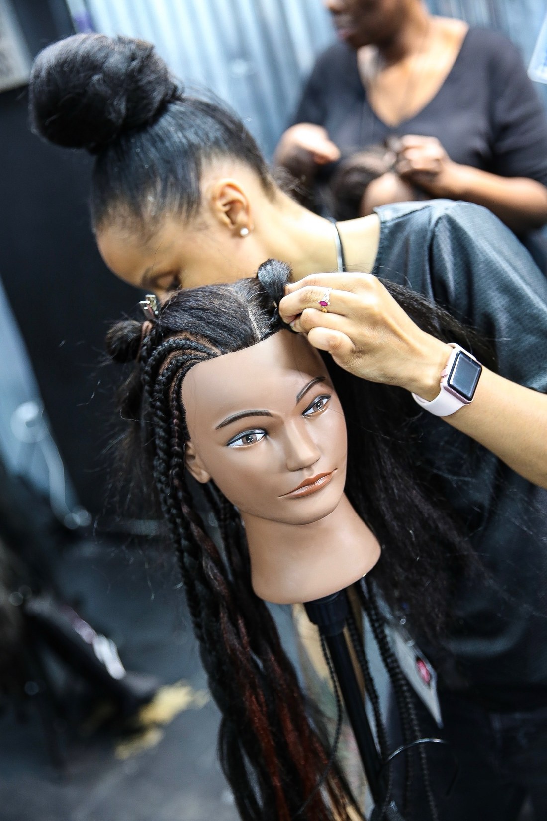 A braider working on a mannequin head at a workshop